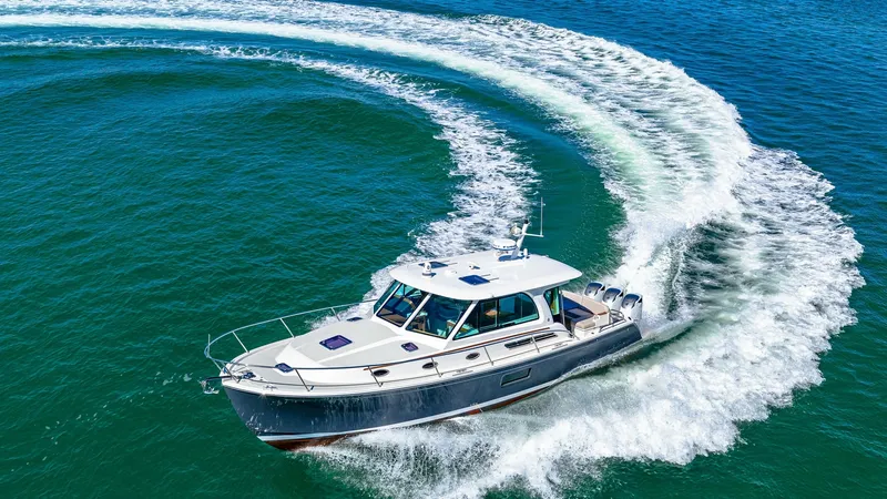 Slide: The Image of Aerial View of Back Cove 390 in Motion This striking aerial shot captures the 2022 Back Cove 390, 'Risk and Reward,' elegantly carving through the water. The vessel's sleek design and powerful performance are highlighted by the dynamic wake trail, showcasing its agility and speed. The spacious - 8738171