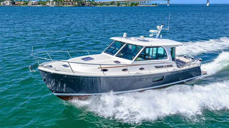 Slide: The Image of Portside View in Motion The Back Cove 390, model year 2022, elegantly glides through the water, showcasing its sleek portside profile. The dark hull contrasts beautifully with the light cabin, accentuated by large windows for optimal visibility and natural light. This vessel's m - 8738166