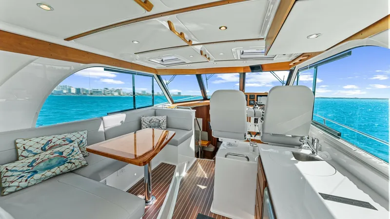Slide: The Image of Spacious Helm and Salon Area The helm and salon area of the 2022 Back Cove 390 showcases a seamless blend of functionality and elegance. Expansive windows offer panoramic ocean views, enhancing the bright and airy atmosphere. The space features plush seating, a stylish wooden table, - 8738122