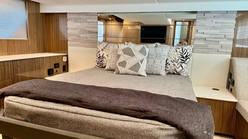 Slide: The Image of Master Stateroom with Modern Decor The master stateroom of the 2024 Cruisers Yachts 50 Cantius exudes luxury with its elegant design and modern decor. Featuring a spacious, plush bed adorned with stylish cushions and a soft throw, the room is surrounded by rich wood paneling and textured w - 8737990