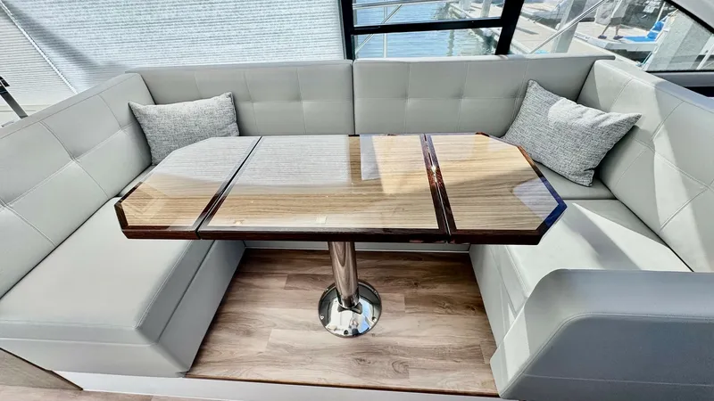 Slide: The Image of Elegant Salon Seating Area The salon of the 2024 Cruisers Yachts 50 Cantius offers a sophisticated seating area with plush, light-colored upholstery and stylish throw pillows. The high-gloss wooden table, set on a sturdy pedestal, provides a perfect spot for dining or casual gather - 8737989