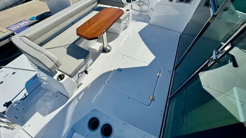 Slide: The Image of Spacious Cockpit Seating Area The cockpit of the 2024 Cruisers Yachts 50 Cantius offers a luxurious outdoor seating area with plush, light-colored cushions and a sleek wooden table. The design ensures comfort and style, perfect for entertaining or relaxing while enjoying the view. Mod - 8738005