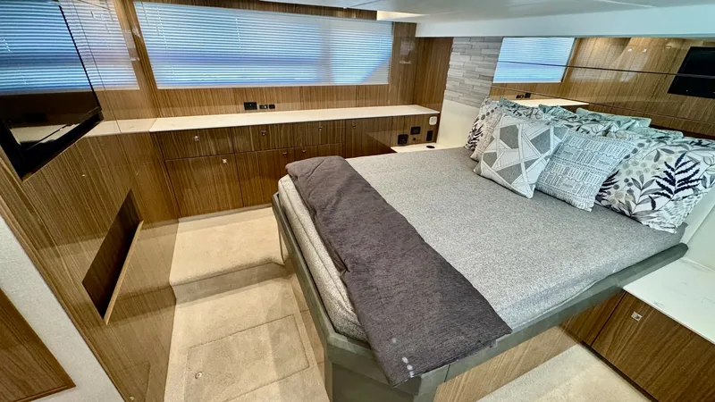 Slide: The Image of Master Stateroom with Modern Amenities The master stateroom of the 2024 Cruisers Yachts 50 Cantius boasts a spacious and luxurious layout. Featuring a plush double bed with contemporary bedding, the room is complemented by warm wood finishes and ample natural light filtering through large wind - 8737992