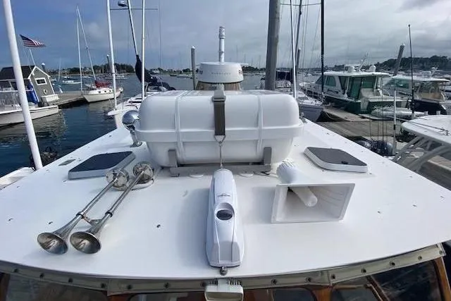 Slide: The Image of 1997 Fortier Hardtop Express boat docked, featuring deck equipment and nearby marina. - 34