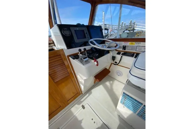 Slide: The Image of 1997 Fortier Hardtop Express boat helm with steering wheel, controls, and navigation equipment. - 35