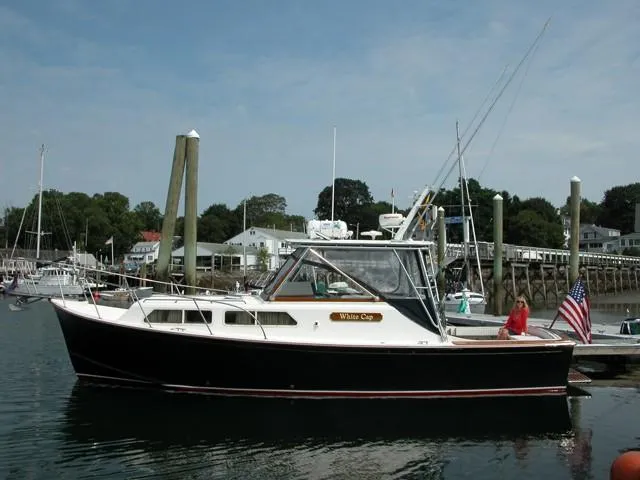 Slide: The Image of 1997 Fortier Hardtop Express boat docked in a marina, featuring classic design and American flag. - 7