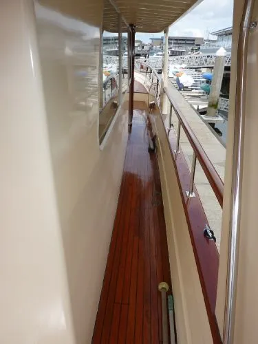 Slide: The Image of 1968 Monk 56 Flushdeck yacht with polished wooden deck and marina view. - 14