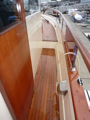 Slide: The Image of 1968 Monk 56 Flushdeck yacht with polished wooden deck and railing, docked at marina. - 21