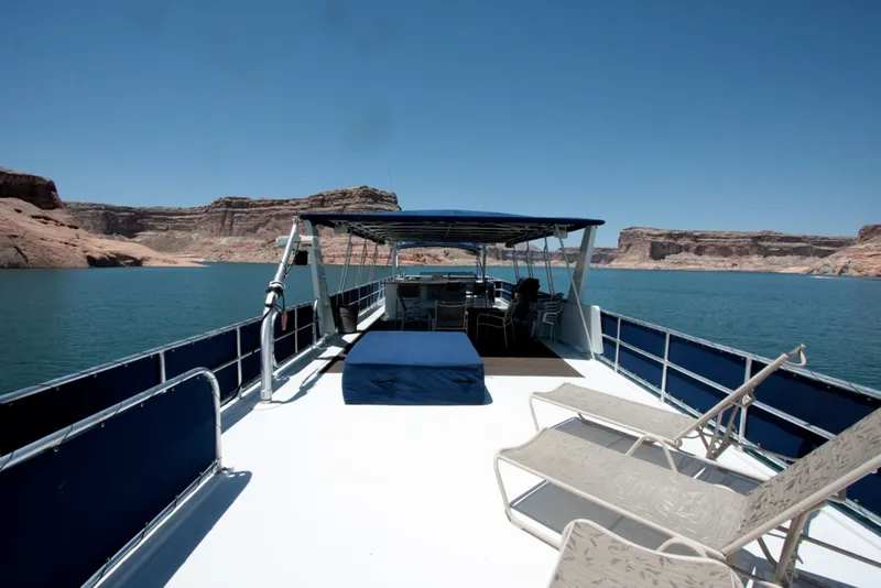 Slide: The Image of Houseboat on a serene lake with lounge chairs, surrounded by rocky cliffs. - 9