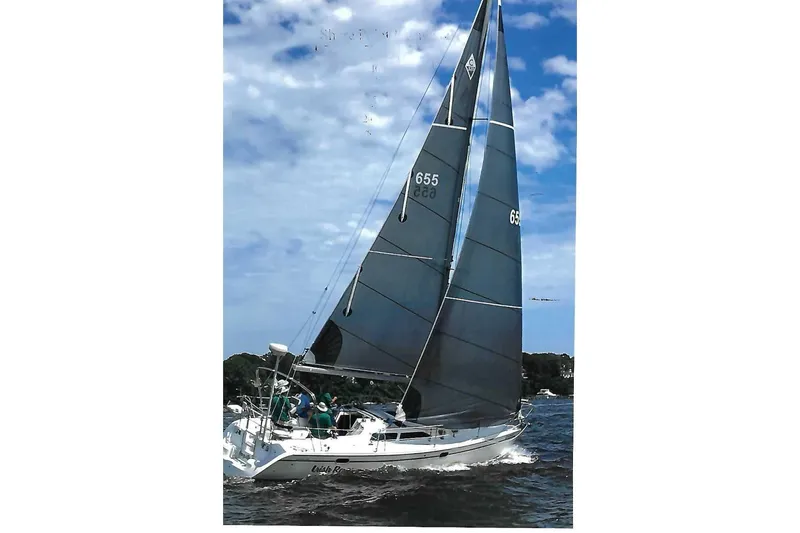 Slide: The Image of Sailing on a 1999 Catalina 320 yacht with dark sails under a partly cloudy sky. - 3