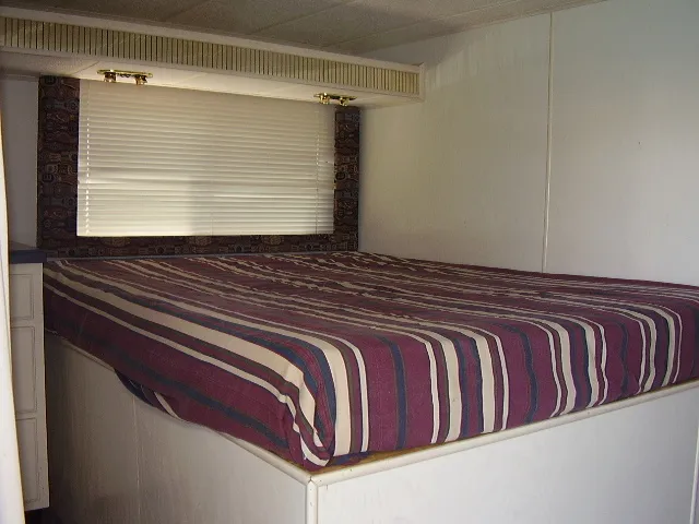 Slide: The Image of 1998 Jamestowner Widebody Multi Owner Houseboat bedroom with striped bedspread and window blinds. - 5