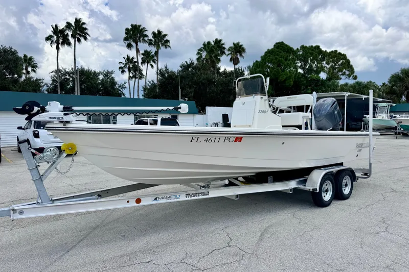 The Image of 2012 Pathfinder 2200 TRS boat on trailer, parked outdoors with palm trees in background. - 4