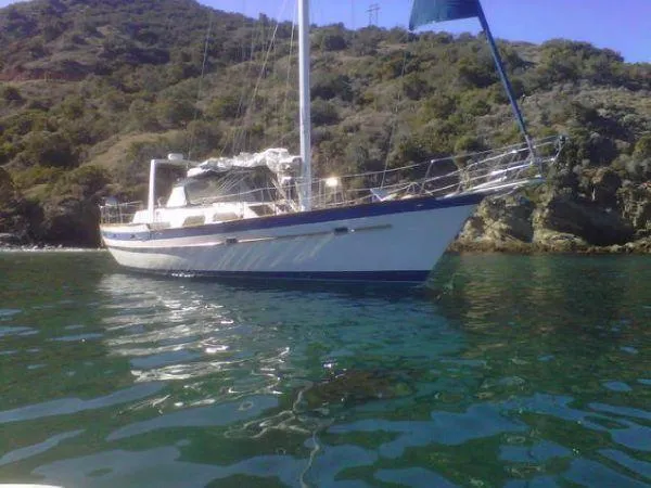 The Image of 1984 Irwin Center Cockpit sailboat near a wooded coastline. - 0