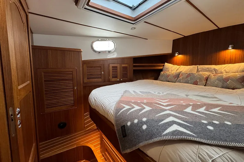 Slide: The Image of 2026 Helmsman Trawlers 38 Sedan cabin interior with cozy bed and wooden finish. - 22