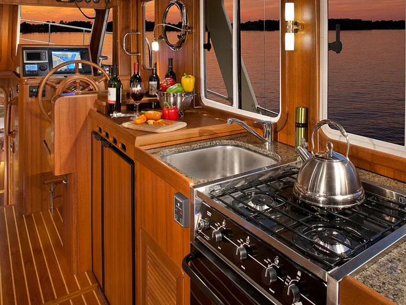 Slide: The Image of Luxurious 2026 Helmsman Trawlers 38 Sedan interior with kitchen and scenic sunset view. - 33