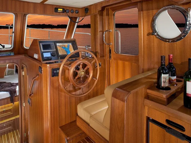 Slide: The Image of Helmsman Trawlers 38 Sedan 2026 interior with wooden helm, navigation equipment, and sunset view. - 34