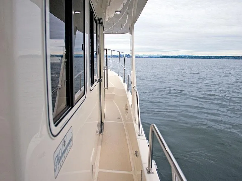 Slide: The Image of 2026 Helmsman Trawlers 38 Sedan yacht, side deck view over calm waters. - 44