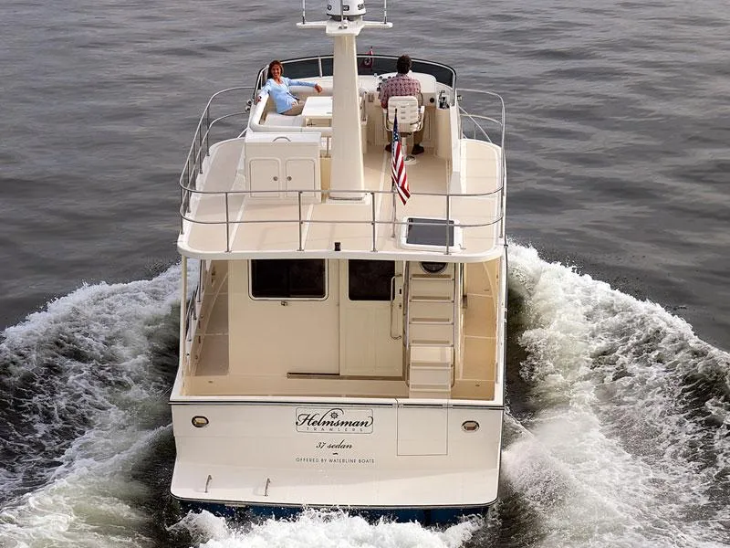 Slide: The Image of 2026 Helmsman Trawlers 38 Sedan cruising on water, rear view with passengers. - 49