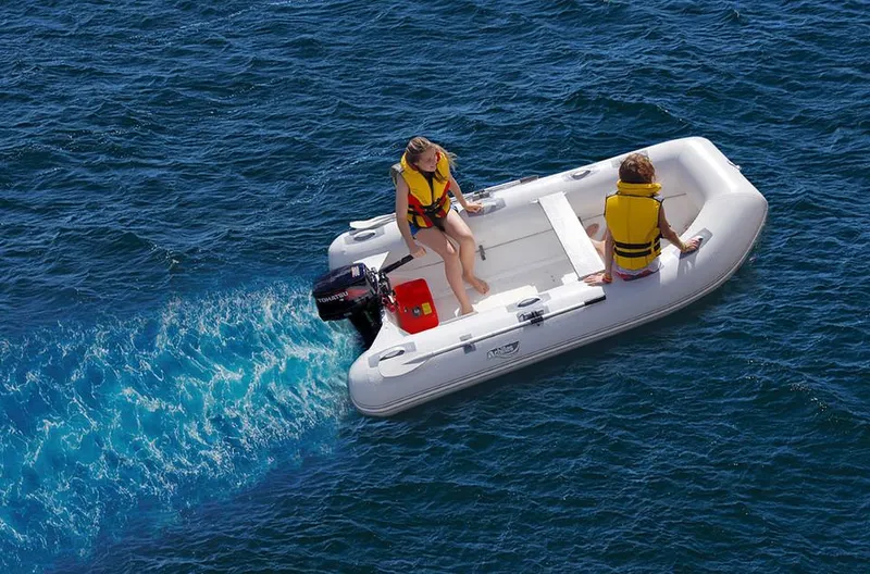 Slide: The Image of 2024 Achilles HB-240LX inflatable boat on water with two people in life jackets. - 3