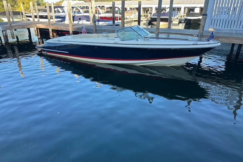 Slide: The Image of 2013 Chris-Craft Corsair 25 boat docked in a marina, reflecting on calm water. - 0