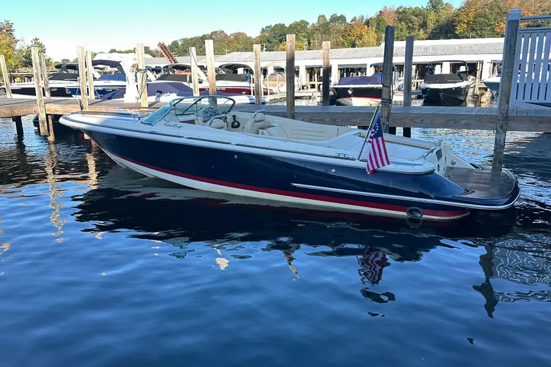 Slide: The Image of 2013 Chris-Craft Corsair 25 boat docked at marina with American flag. - 1
