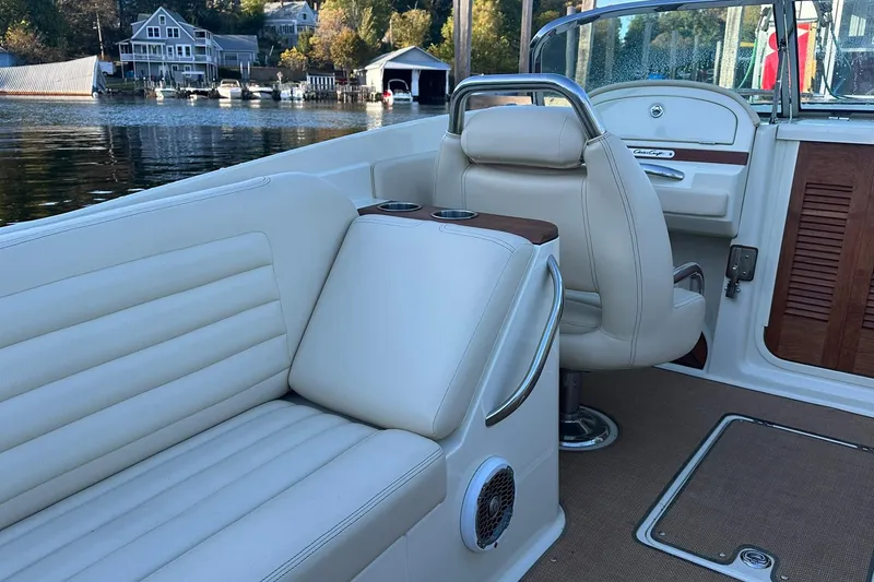 Slide: The Image of 2013 Chris-Craft Corsair 25 boat interior with beige seating and waterfront view. - 10
