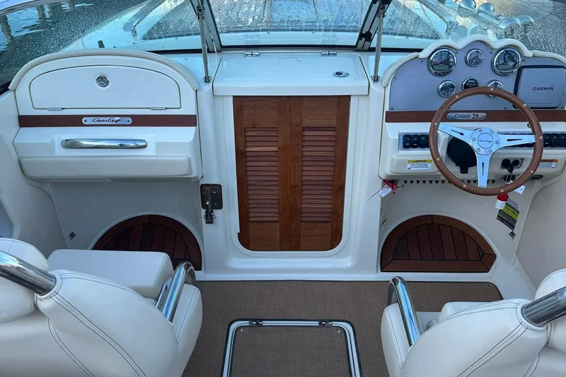 Slide: The Image of 2013 Chris-Craft Corsair 25 boat interior with wooden accents and steering wheel. - 12