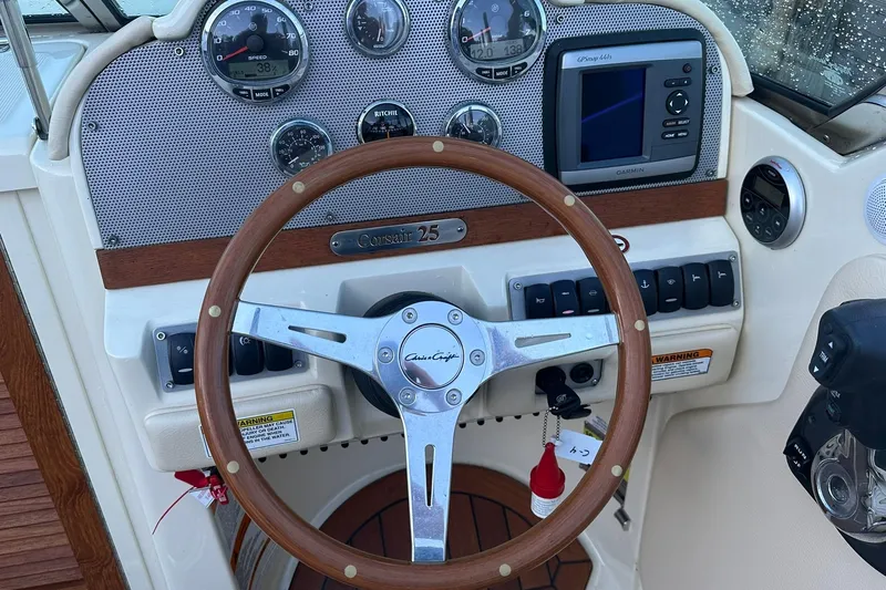Slide: The Image of 2013 Chris-Craft Corsair 25 dashboard with wooden steering wheel and navigation instruments. - 13