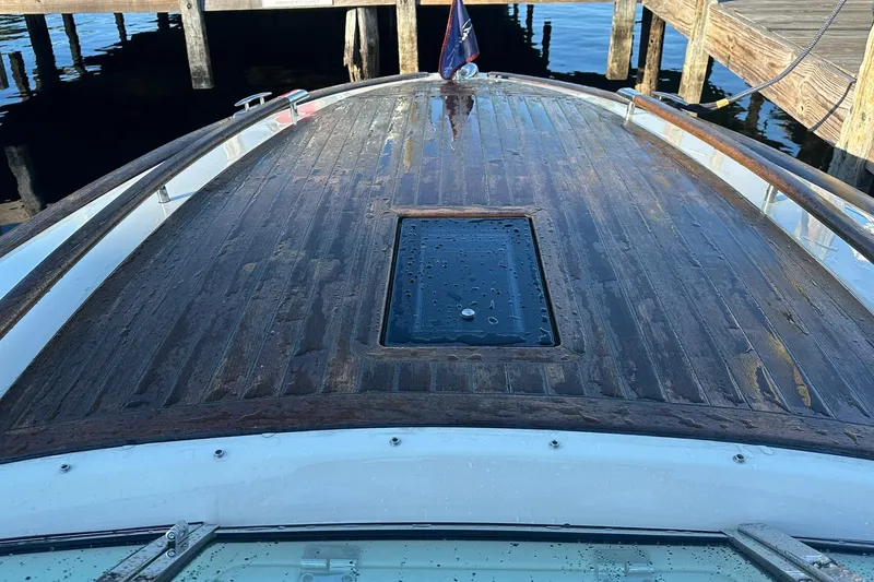 Slide: The Image of 2013 Chris-Craft Corsair 25 boat deck with wooden finish, docked by the water. - 14