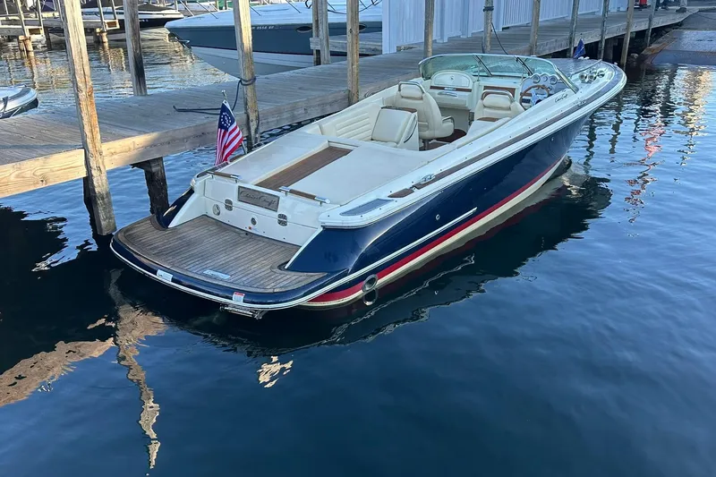 Slide: The Image of 2013 Chris-Craft Corsair 25 boat docked, featuring elegant design and American flag. - 4