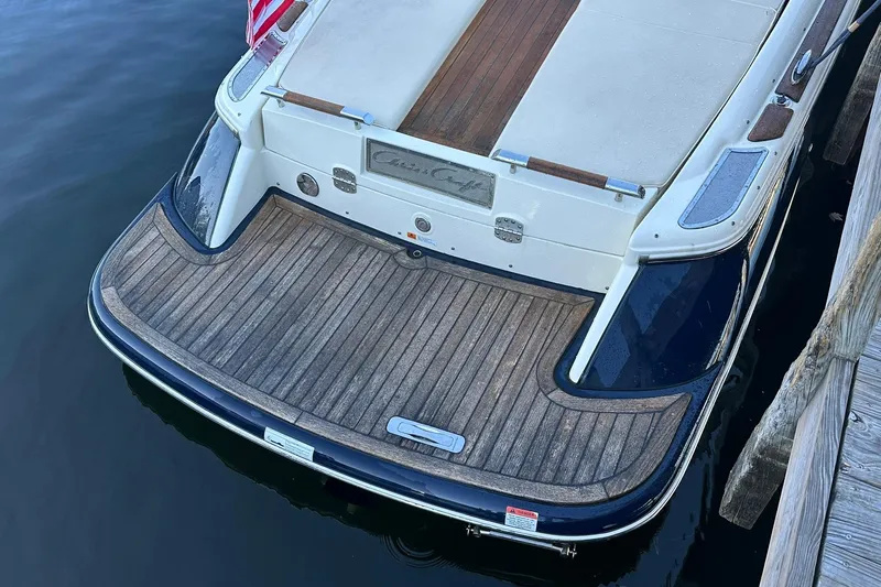 Slide: The Image of 2013 Chris-Craft Corsair 25 boat with wooden deck, docked by the water. - 8