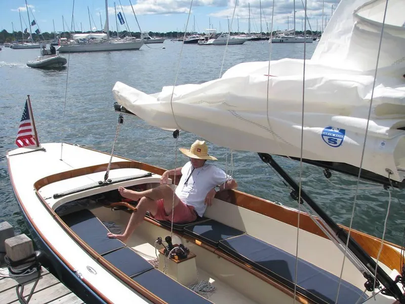 Slide: The Image of 2026 C.W. Hood 32 Daysailer docked, with a person relaxing onboard, surrounded by other boats. - 2