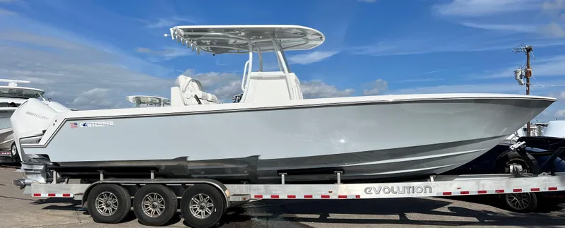 Slide: The Image of 2024 Contender 32 ST boat on a trailer under a clear blue sky. - 2