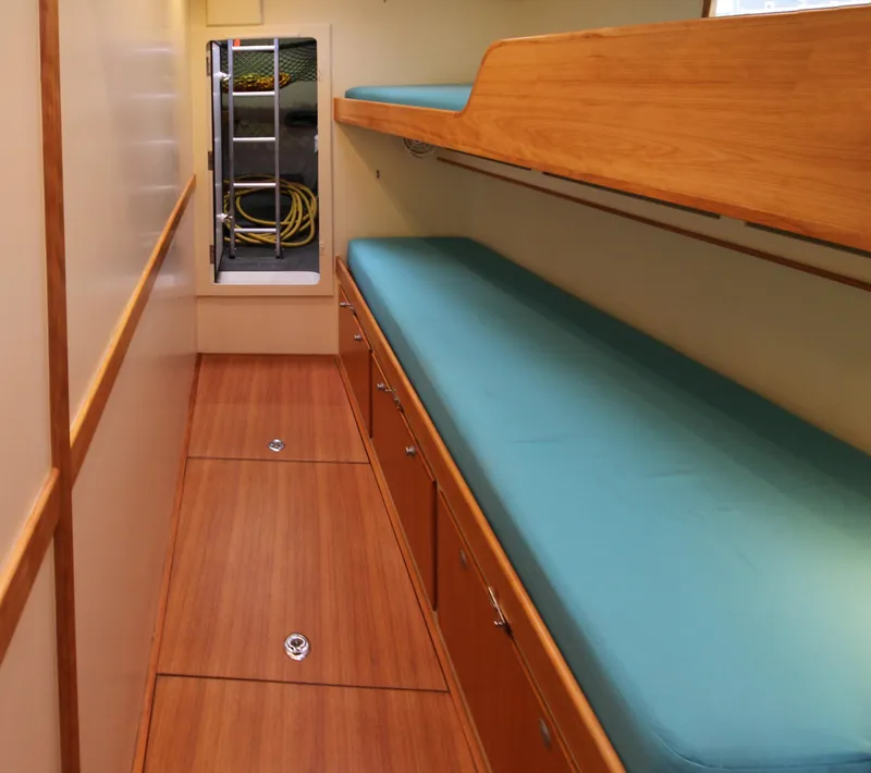 Slide: The Image of Interior of 2026 Lyman Morse Farr Racer-Cruiser, featuring wooden bunk beds and storage. - 16