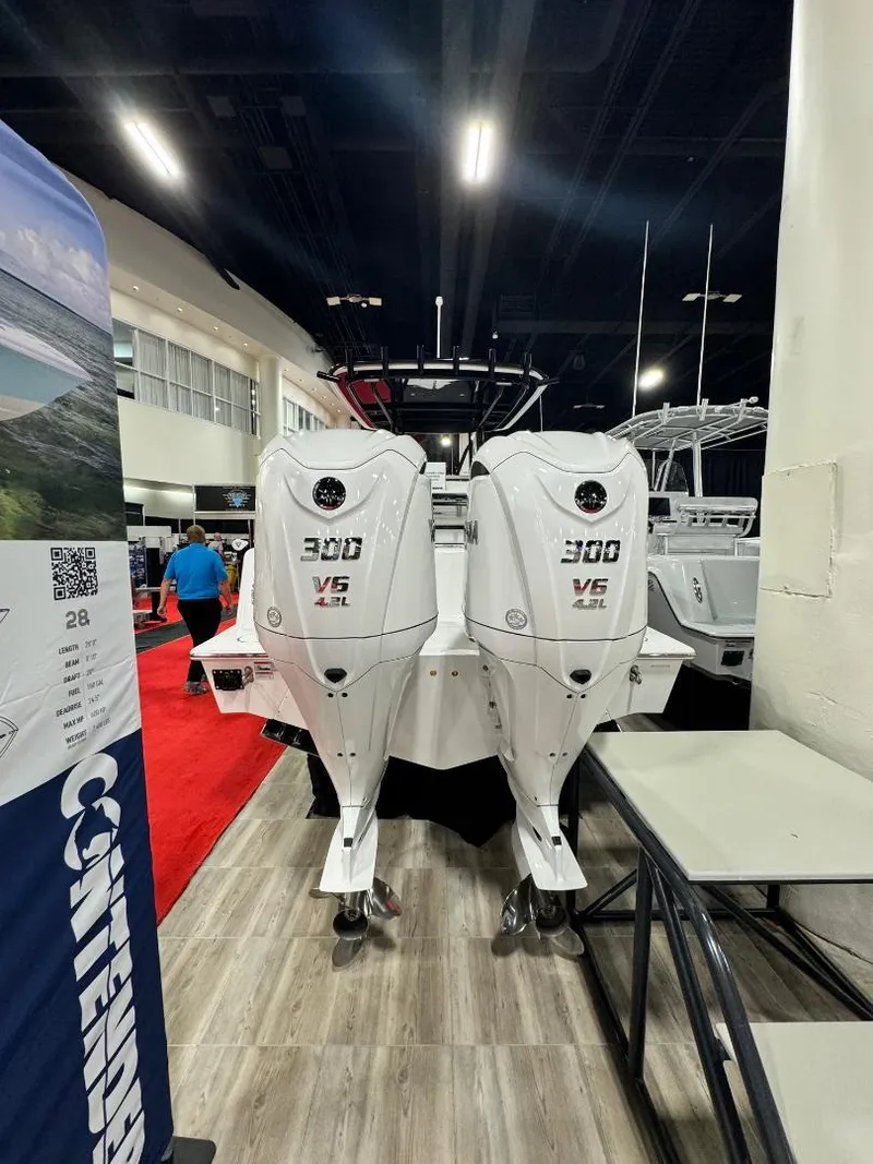Slide: The Image of 2025 Contender 28S boat with dual 300 V6 engines displayed indoors. - 2