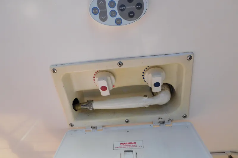 Slide: The Image of Boat shower controls on a 2002 Rinker Fiesta Vee 310, featuring hot and cold knobs. - 11