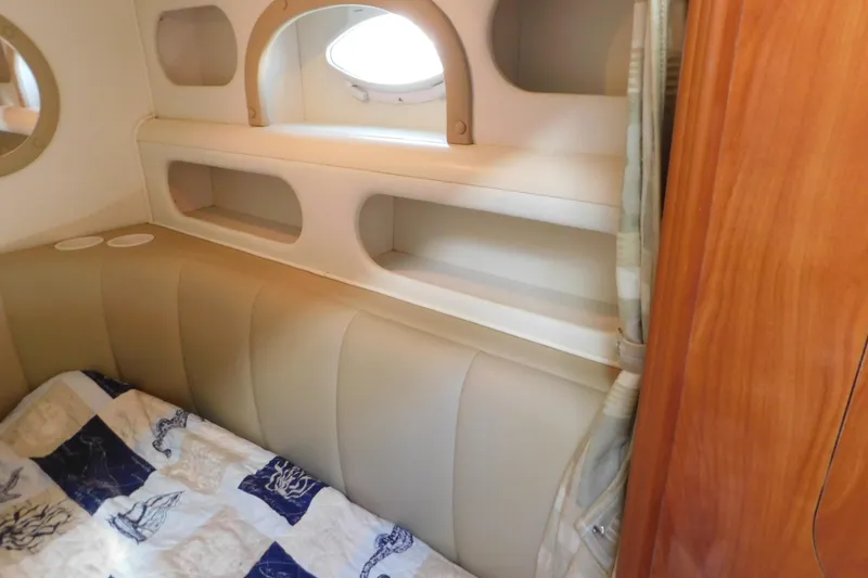 Slide: The Image of Interior cabin of 2002 Rinker Fiesta Vee 310 with beige seating and nautical-themed bedding. - 34