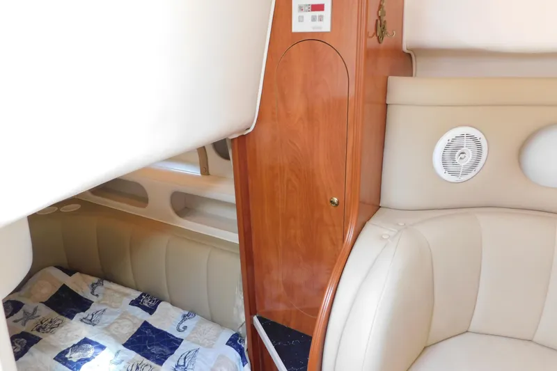 Slide: The Image of 2002 Rinker Fiesta Vee 310 cabin interior with beige seating and nautical-themed bedding. - 35