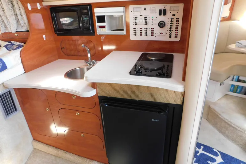 Slide: The Image of 2002 Rinker Fiesta Vee 310 boat interior with kitchenette, featuring sink, stove, and microwave. - 43