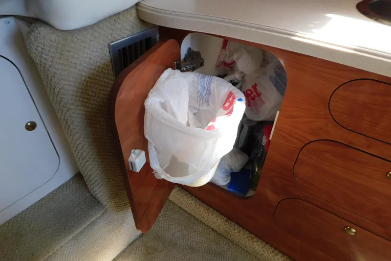 Slide: The Image of 2002 Rinker Fiesta Vee 310 cabin storage with open wooden cabinet and trash bag. - 50