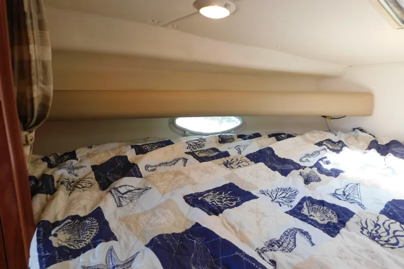 Slide: The Image of Cozy cabin interior of 2002 Rinker Fiesta Vee 310 with nautical-themed bedding. - 55