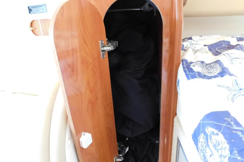 Slide: The Image of Open wooden cabinet on 2002 Rinker Fiesta Vee 310 boat, next to patterned bedding. - 57