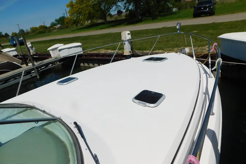 Slide: The Image of 2002 Rinker Fiesta Vee 310 boat docked, showcasing sleek deck design and hatches. - 73