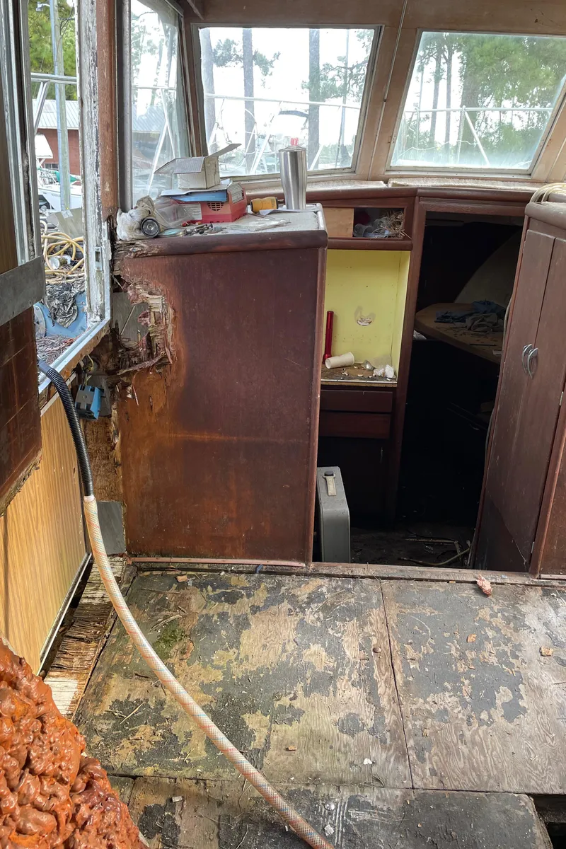 Slide: The Image of 1964 Hatteras Double Cabin interior with visible water damage and worn flooring. - 10