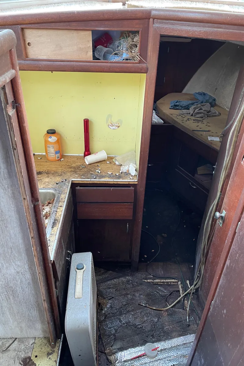 Slide: The Image of 1964 Hatteras Double Cabin interior with cluttered kitchen and sleeping area. - 11