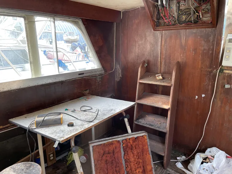 Slide: The Image of 1964 Hatteras Double Cabin interior needing renovation, featuring a work table, shelves, and exposed wiring. - 2
