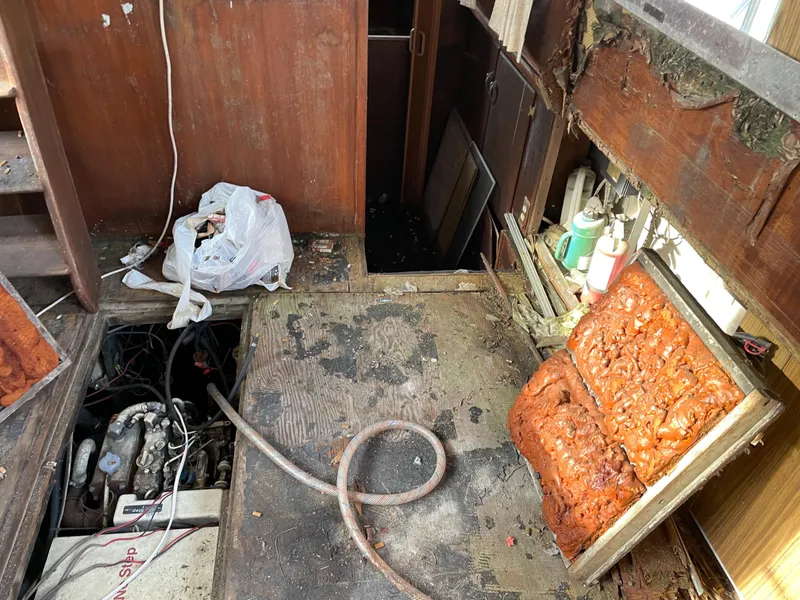 Slide: The Image of 1964 Hatteras Double Cabin interior in need of restoration, showing engine and damaged seating. - 4