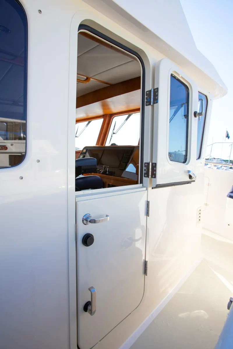 Slide: The Image of 2025 Krogen 58 Extended Bridge yacht, open cabin door, sleek white exterior. - 33