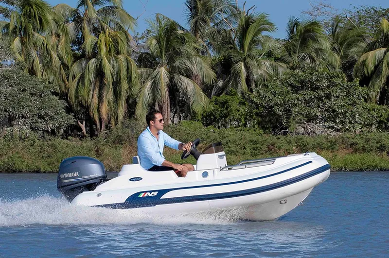 Slide: The Image of 2024 AB Inflatables Nautilus 11 DLX boat cruising on water with lush greenery in the background. - 4