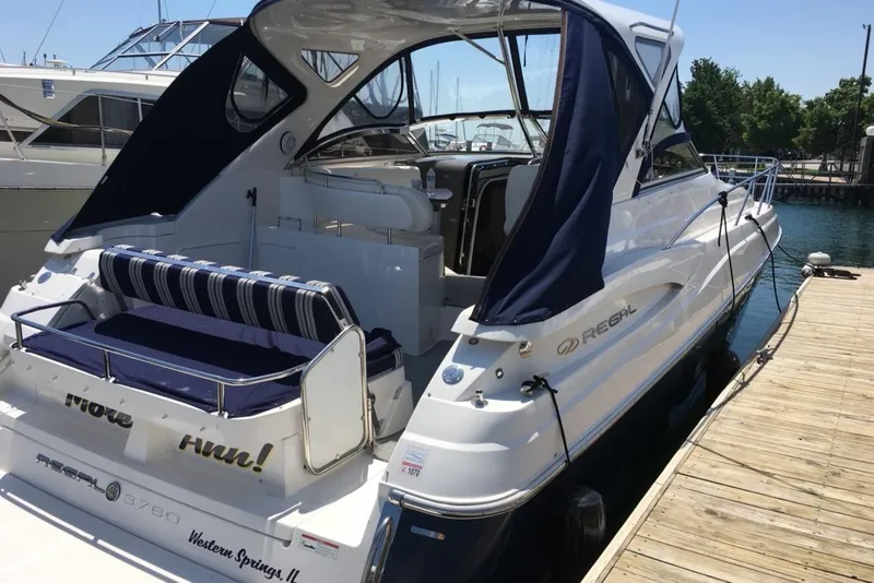 Slide: The Image of 2008 Regal 3760 yacht docked at a marina with blue canopy and striped seating. - 2